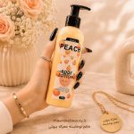بطری پمپی لوسیون بدن هلو آنیلا ۲۵۰ گرمی حاوی شی باتر و روغن نارگیل در دست خانم با ناخن مشکی در فروشگاه معرکه بیوتی