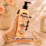 بطری پمپی لوسیون بدن هلو آنیلا ۲۵۰ گرمی حاوی شی باتر و روغن نارگیل در دست با پس‌زمینه گل‌های رز در فروشگاه معرکه بیوتی